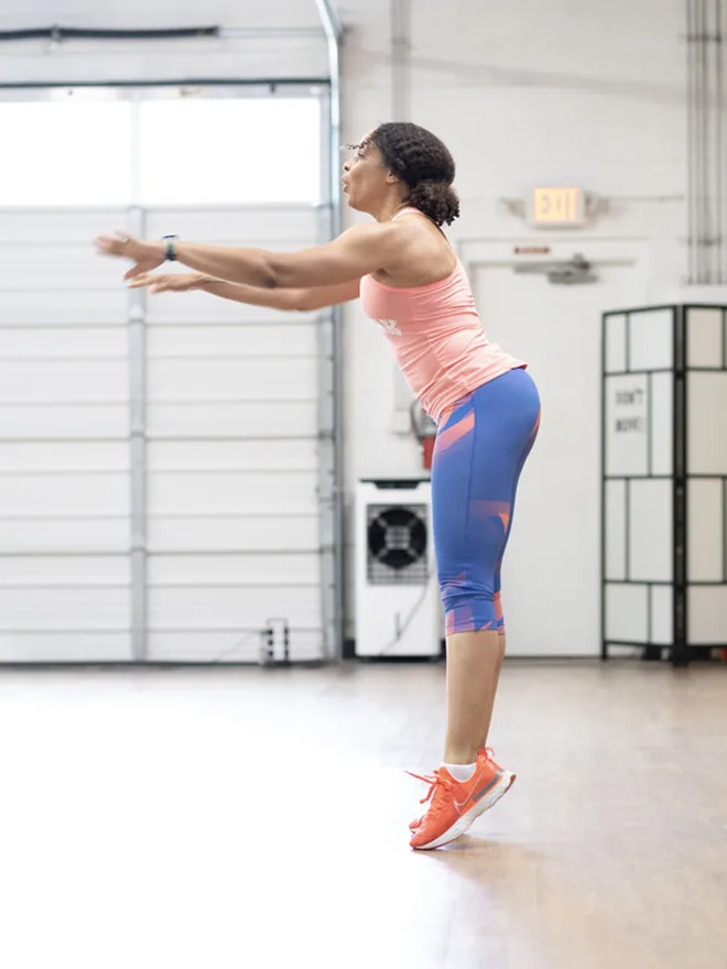 Sophie hinged forward with both arms reaching out, mid dance-cardio combination.