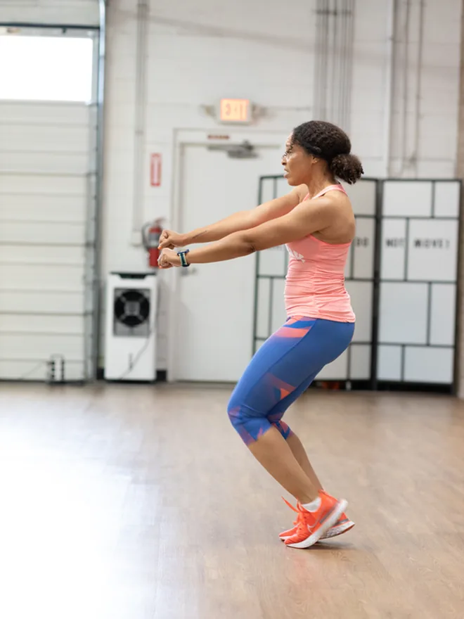 Sophie in a low squat with her arms drawn in, mid strength block.